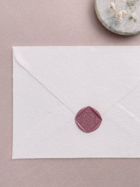 Dusty rose square wax seal featuring quatrefoil Talavera pattern on a white handmade paper envelope
