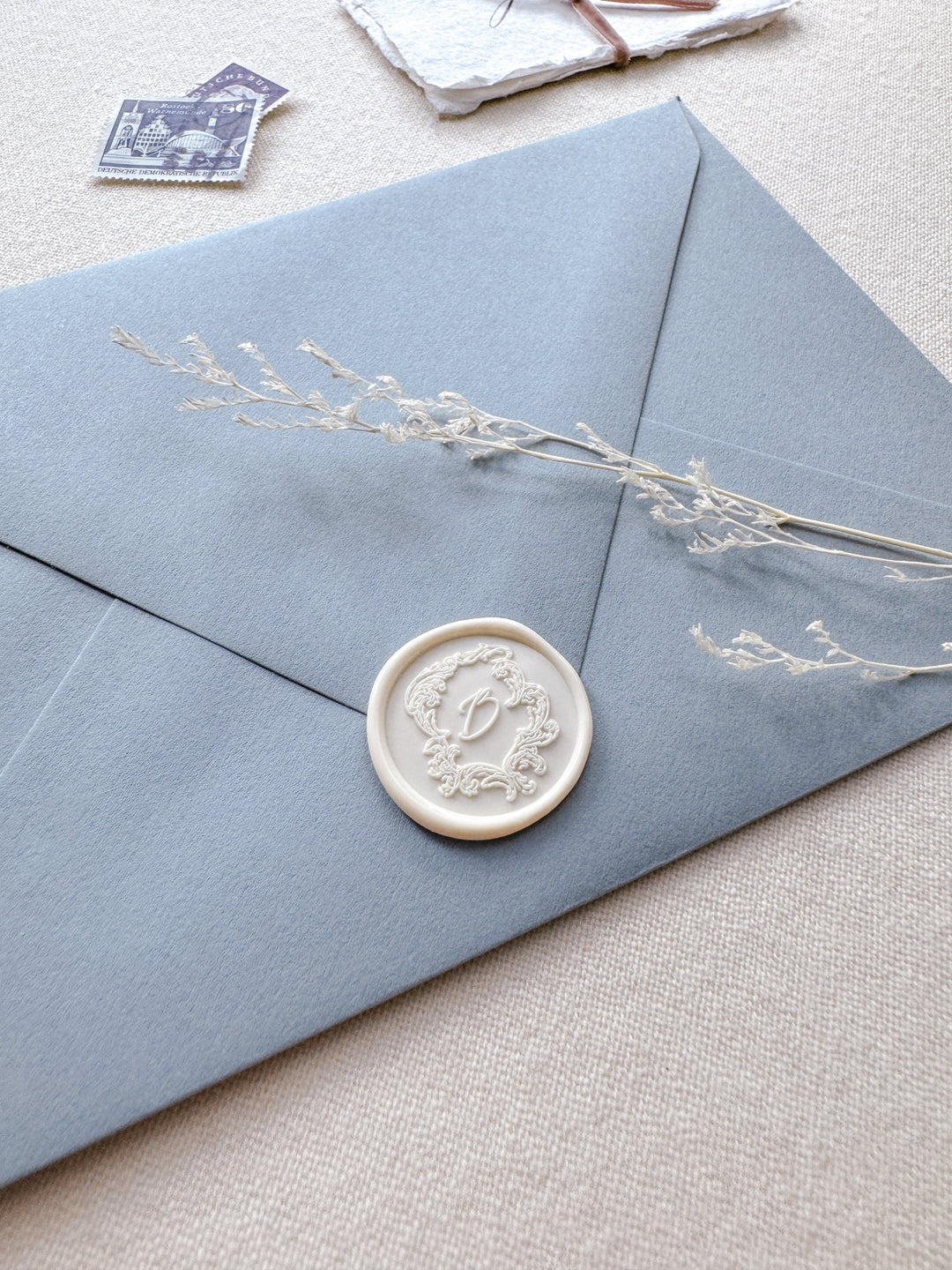antique white vintage Baroque crest  monogram wax seal on a dusty blue envelope