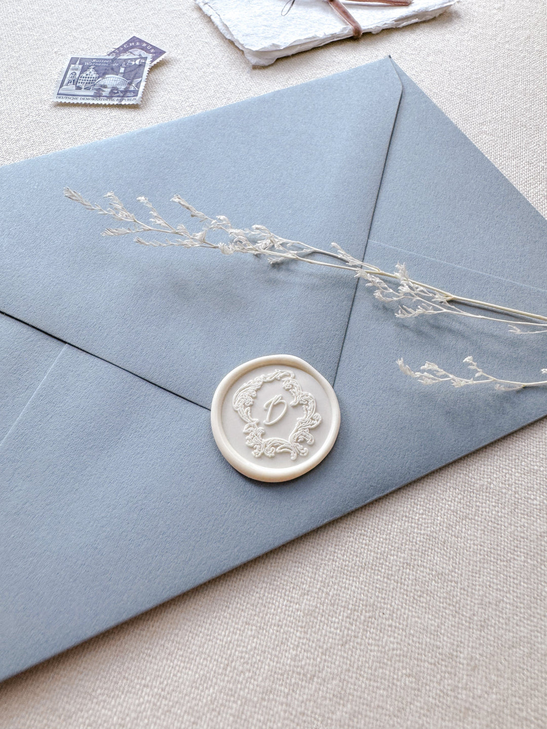 off-white vintage crest monogram wax seal on dusty blue envelope