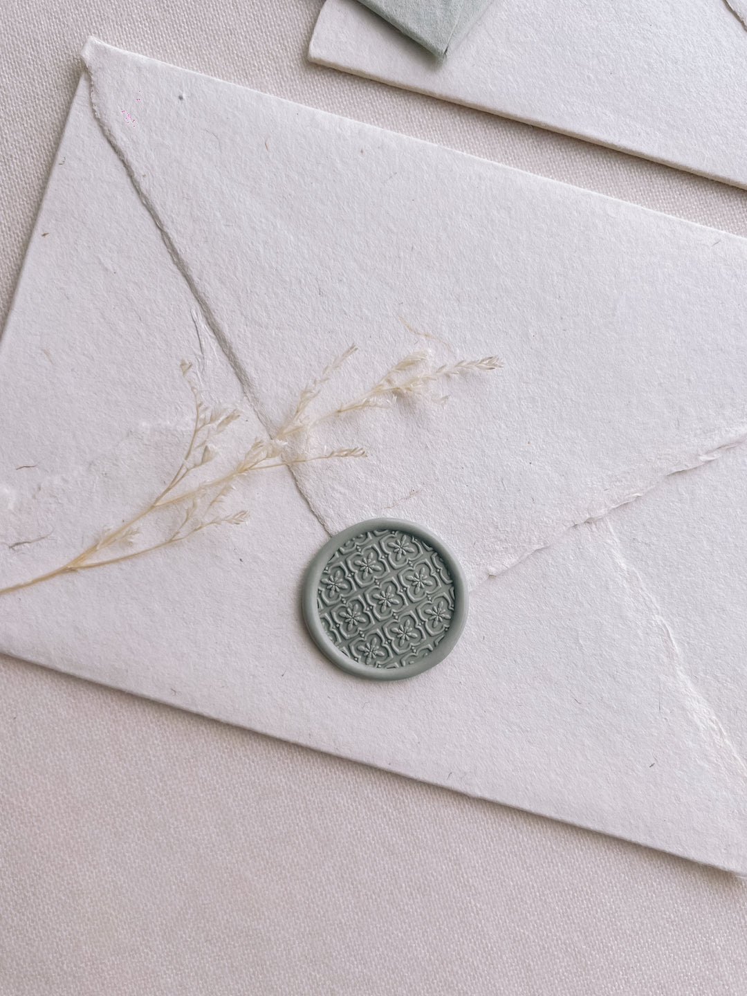 moroccan tile pattern wax seal in sage color on a white handmade paper envelope 