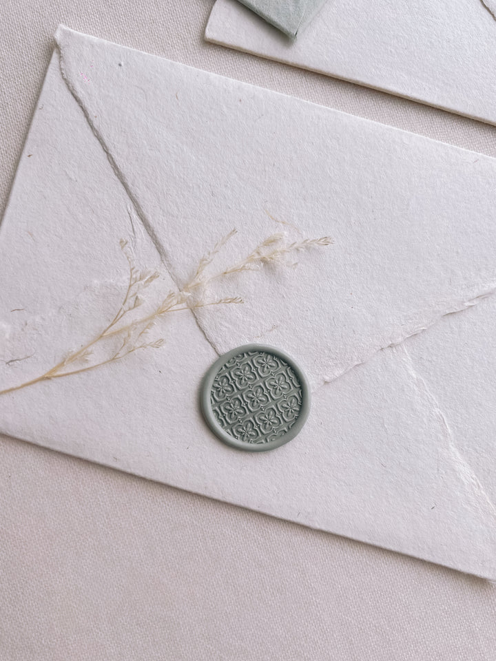 moroccan tile pattern wax seal in sage color on a white handmade paper envelope 