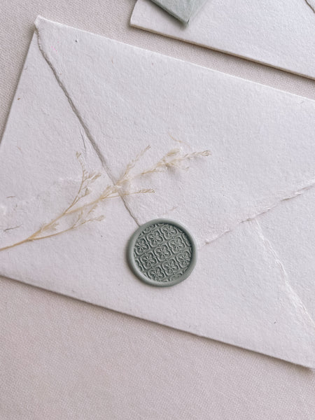 moroccan tile pattern wax seal in sage color on a white handmade paper envelope 