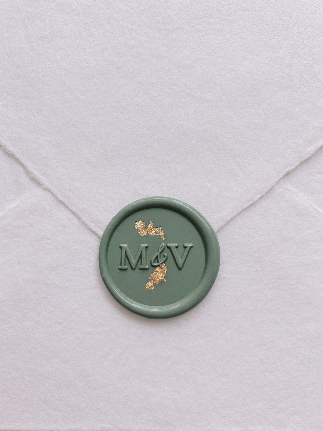 modern monogram wax seal in sage green embellished with gold leaf on handmade paper envelope_front angle