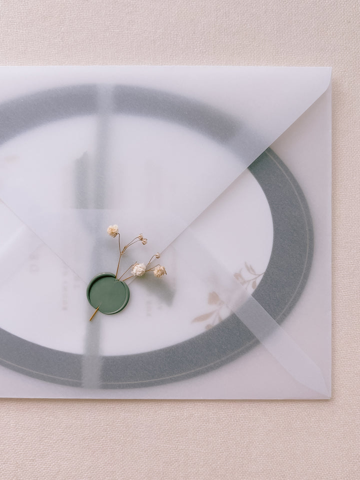 blank wax seal in sage green embellished with white dried flowers on vellum envelope