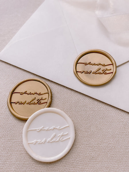 Save our date wax seals in light gold and off white styled with a strand of white silk ribbon