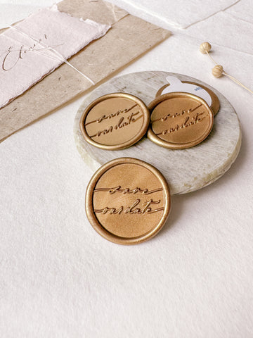 Calligraphy script "save our date" gold wax seals styled with a small gray stone dish, handmade paper and a dried floral branch