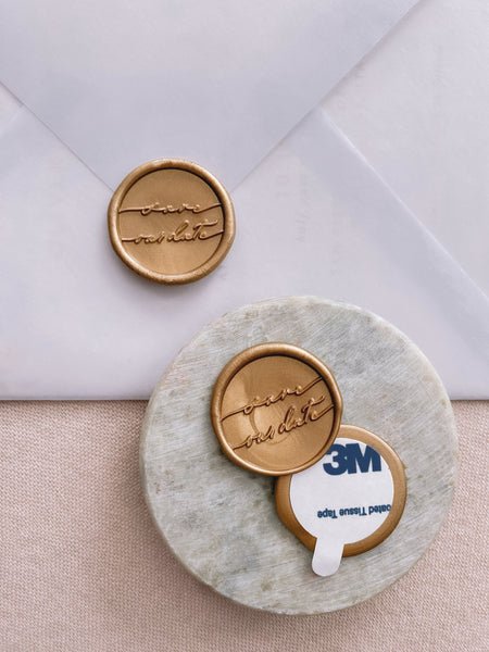Save our date wax seals in gold with 3m stickers on small gray stone dish