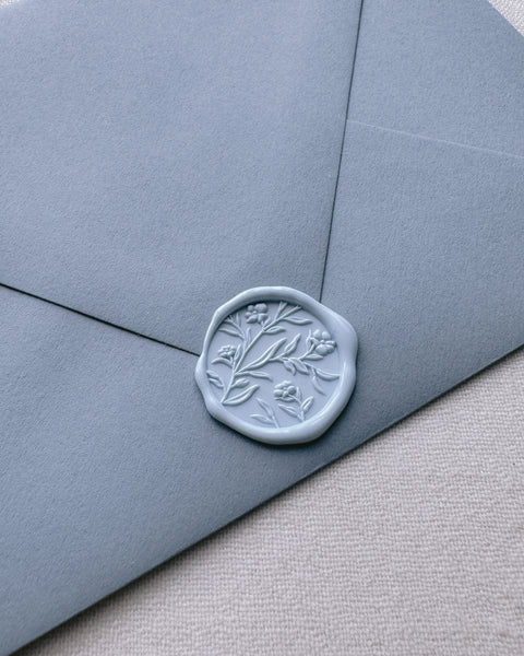 Light blue floral pattern wax seal with 3D engraving details on a dusty blue envelope