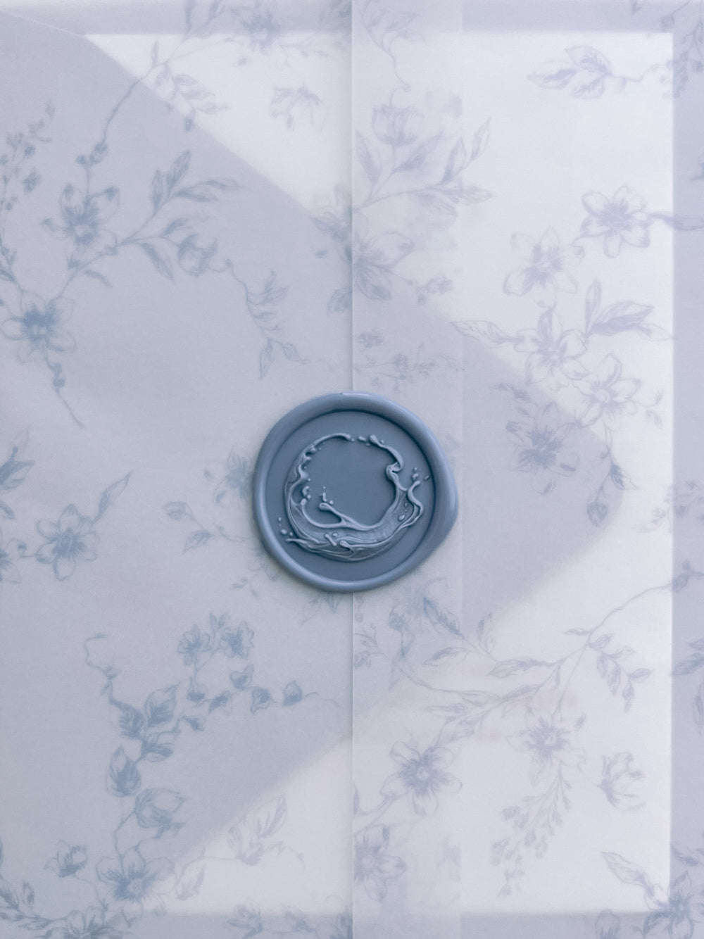 Dusty blue 3D sculpted ocean waves wax seal on a blue floral print vellum jacket