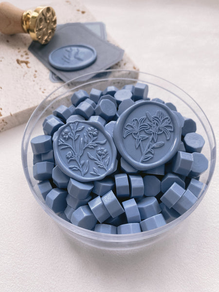a box of dusty blue sealing wax beads with scarlette 3d floral seal and lily oval wax seal in dusty blue color