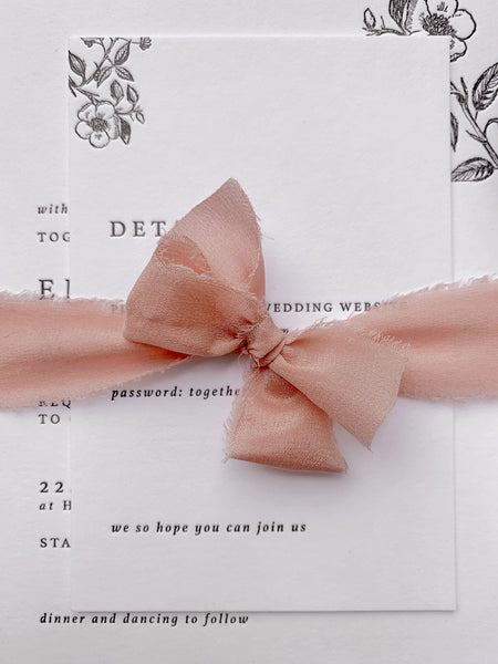 1 inch  raw edge silk ribbon in color Blush tied in a bow on a letterpress invitation suite
