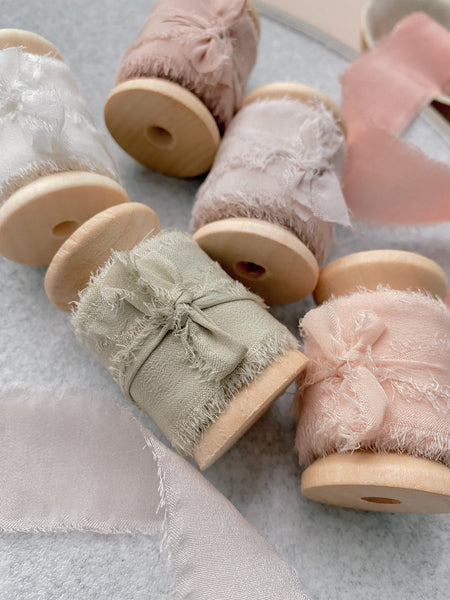 1 inch raw edge silk ribbon on wooden spools in color Soft White, Nude Grey, Dusty Blush, and Cream White_closeup