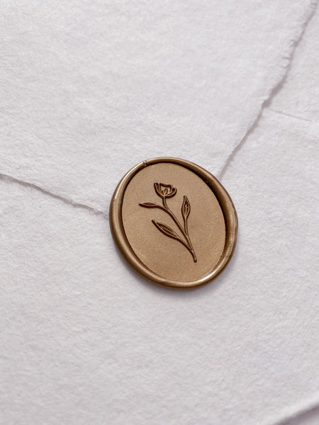 Simple flower oval wax seal in gold on handmade paper envelope_side angle