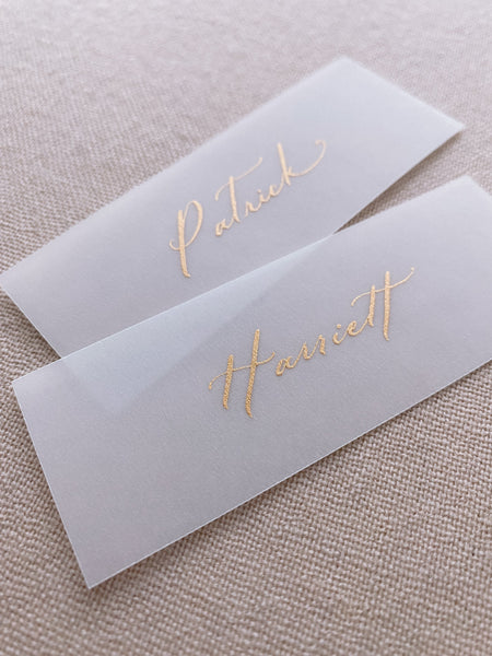 slim vellum place cards in hand lettered calligraphy in gold ink_closeup side angle