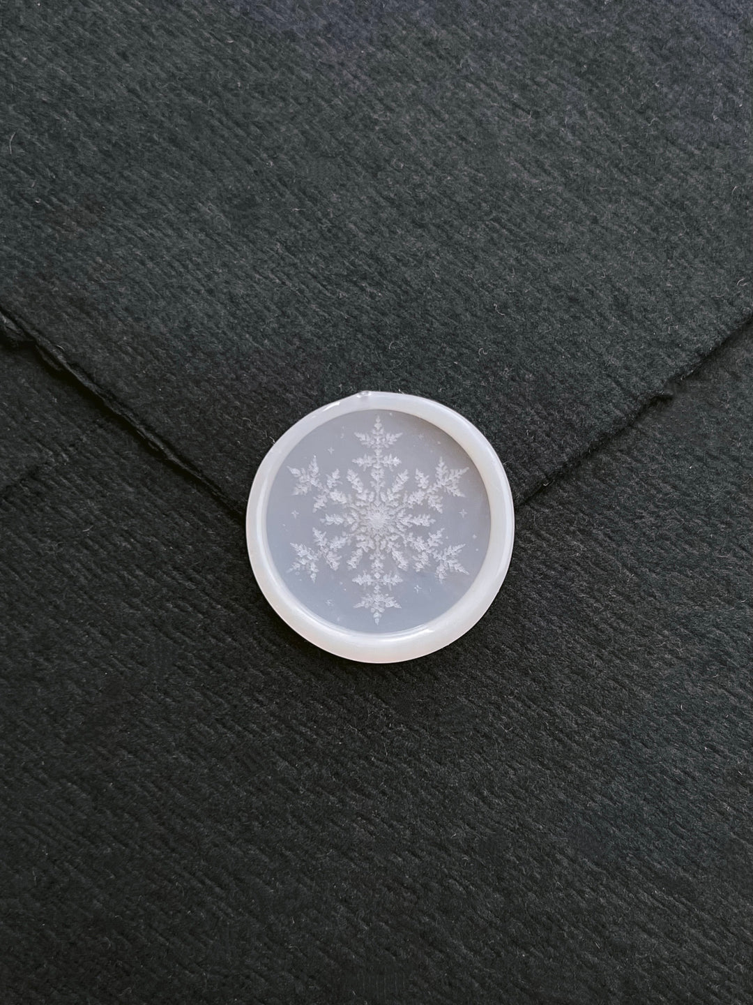 vellum semi-transparent snowflake design wax seal on a black envelope