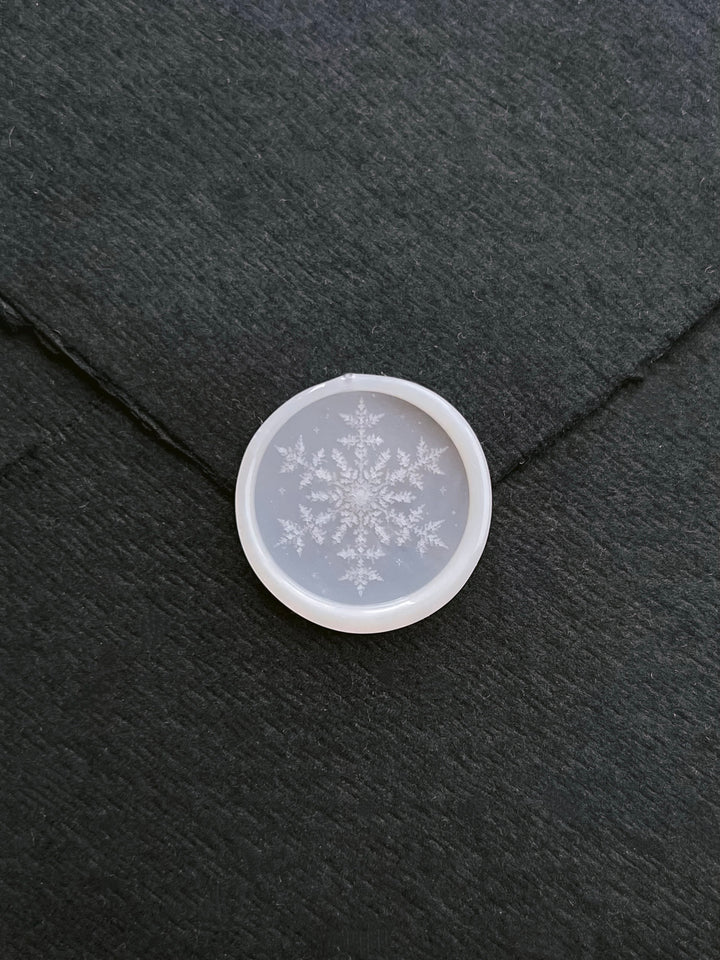 vellum semi-transparent snowflake design wax seal on a black envelope