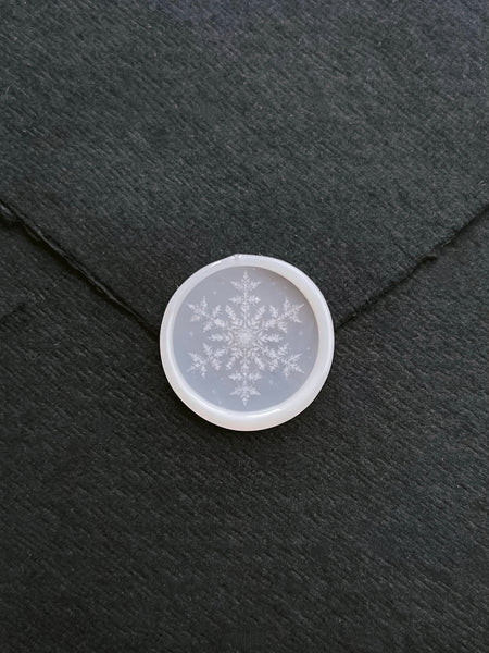 vellum semi-transparent snowflake design wax seal on a black envelope 