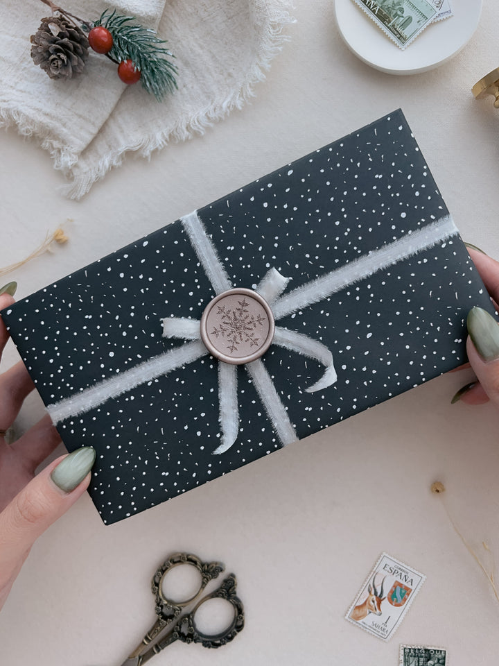 light bronze laser engraved snowflake wax seal on a wrapped Christmas gift