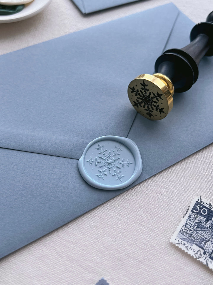 light blue snowflake wax seal on a dusty blue envelope