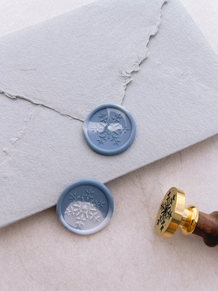White and blue marbled wax seals with snowflake design on light gray envelope