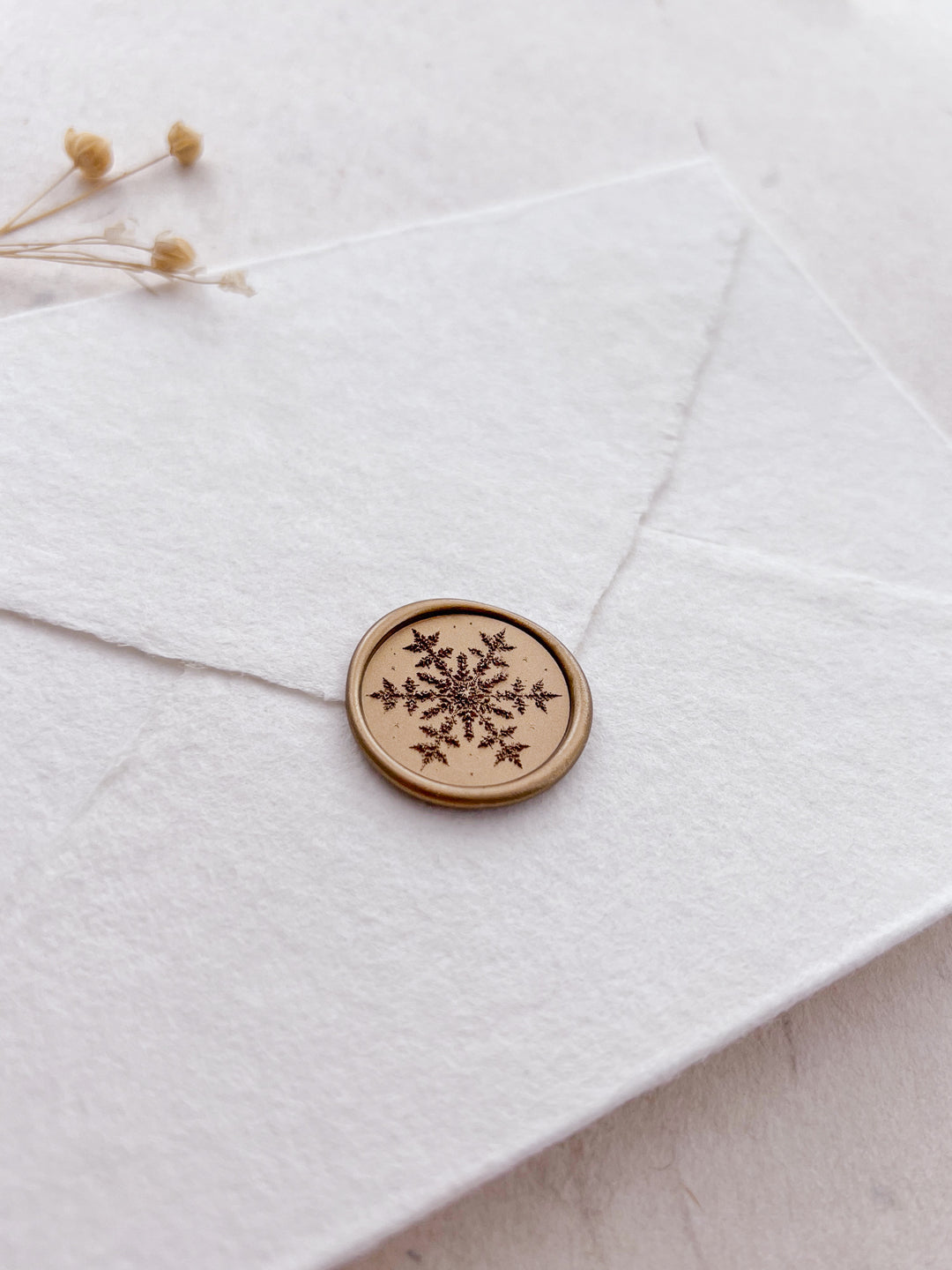 snowflake design gold wax seal on a white envelope