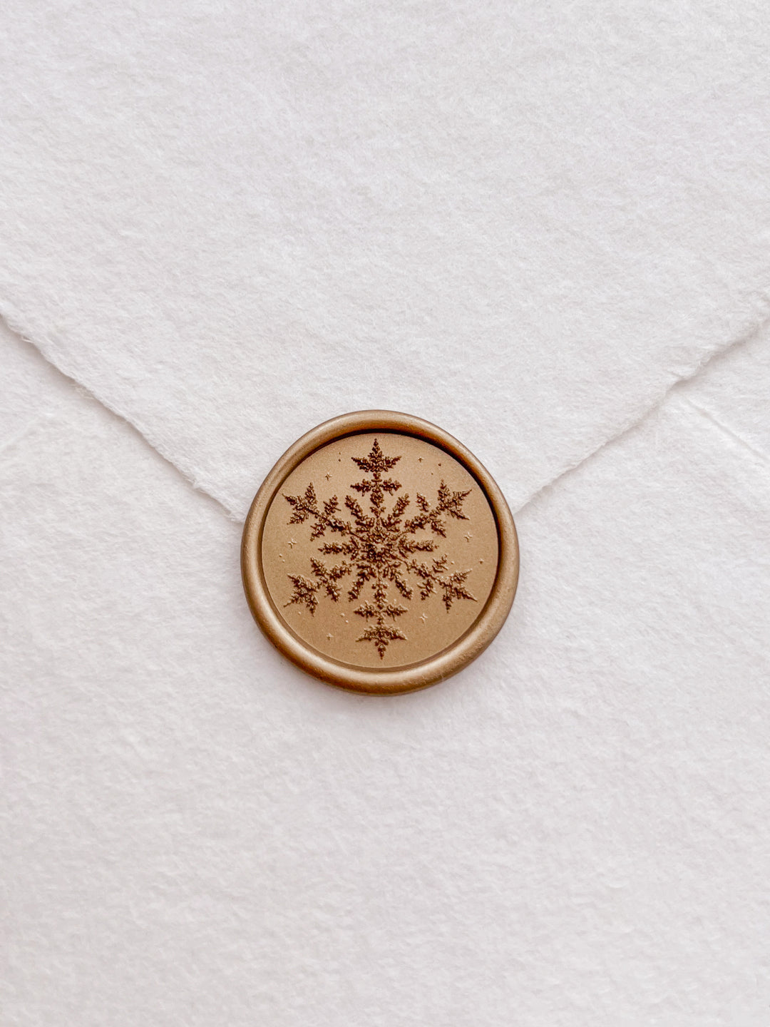 Gold 3D snowflake wax seal on a white deckled edge handmade paper envelope