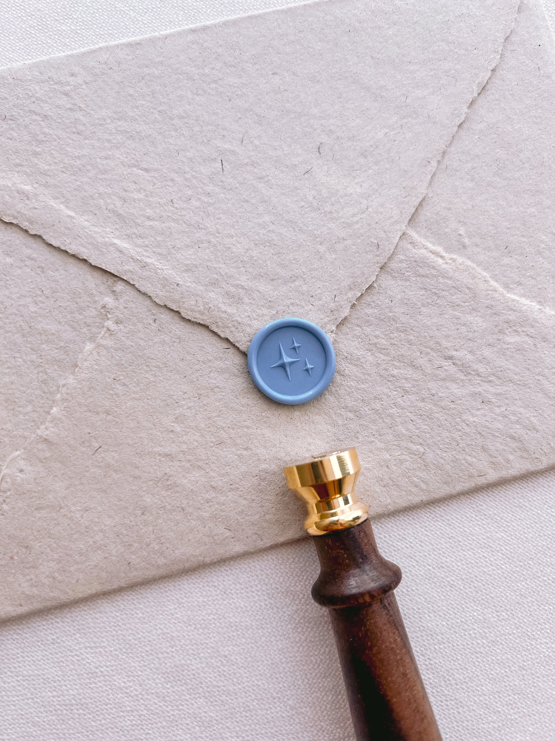 dusty blue 3D star emoji mini wax seal on a beige envelope 