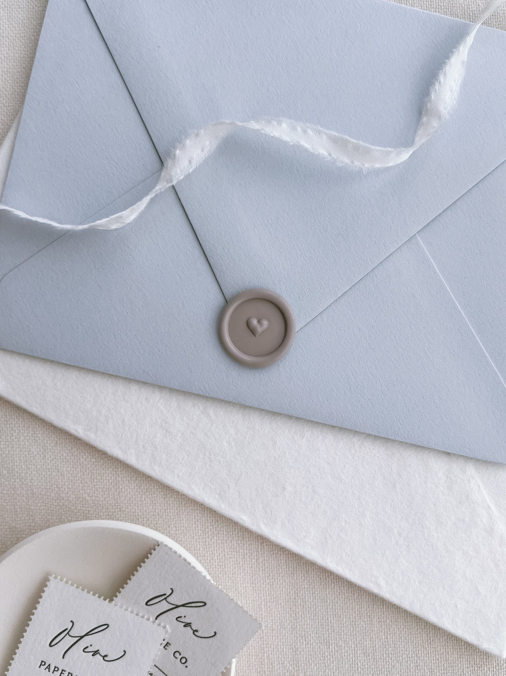 3D heart design taupe wax seal on a light blue envelope