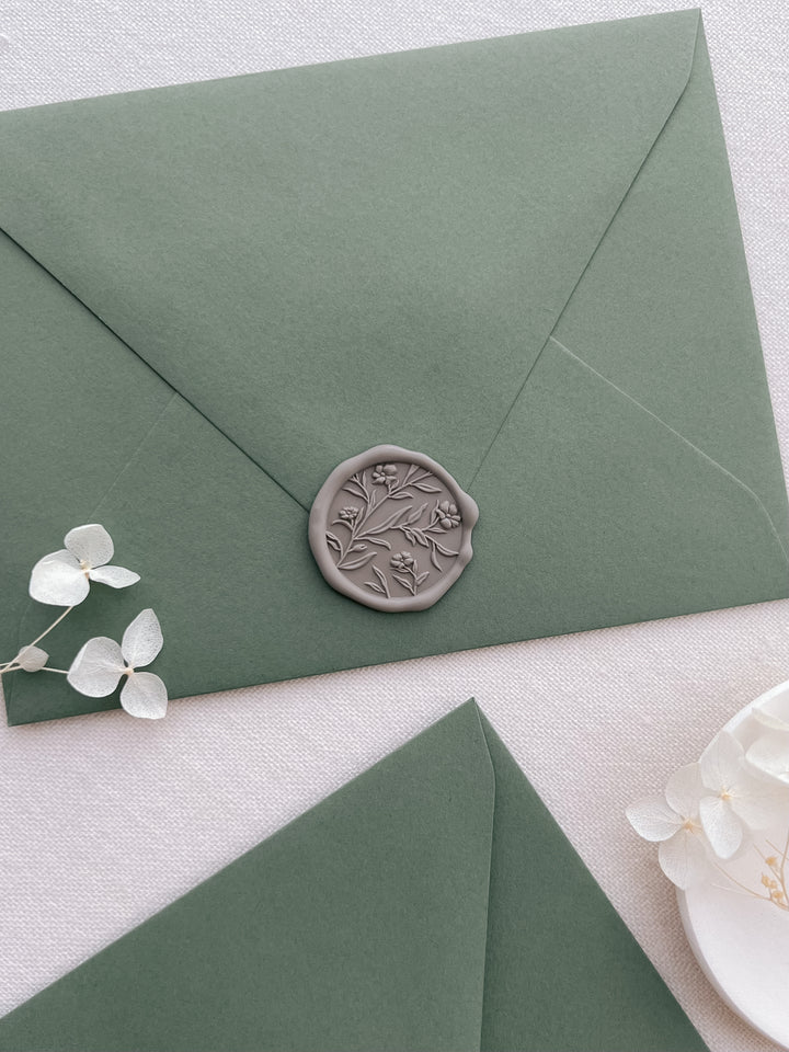 taupe colored 3D floral pattern wax seal on an olive green envelope