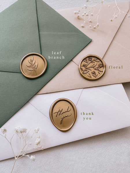 gold wax seal labeled with design names on olive green, beige and white envelopes