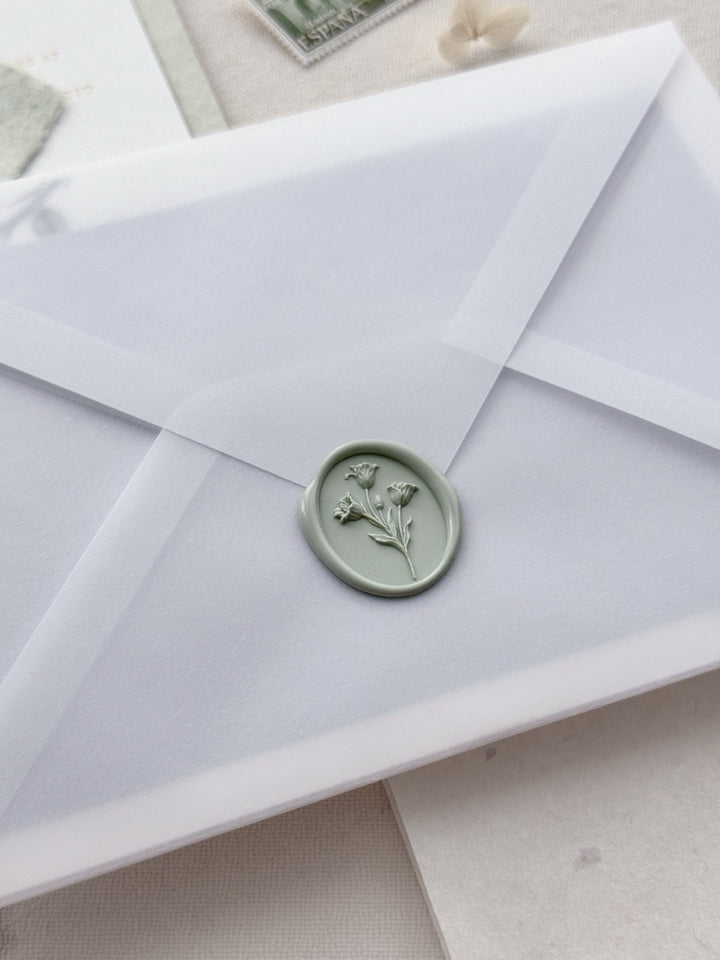 Sage green tulip wax seal stamp on a vellum envelope.
