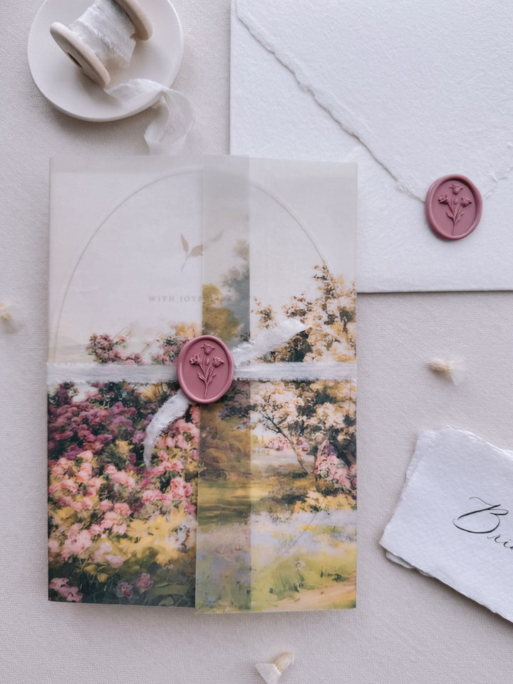 Mauve pink tulip oval wax seal on a watercolor garden-themed vellum wrap tied with white silk ribbon, set against a wedding invitation suite.