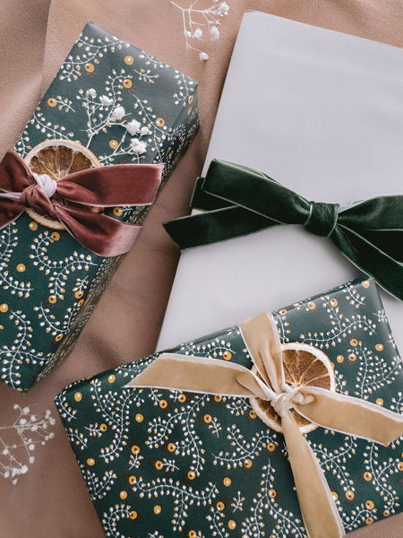 Christmas gifts wrapped in festive gift wrapping and decorated with green, gold and rust velvet ribbons 