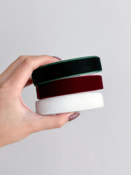 three rolls of velvet ribbons in color dark green, dark red, and white