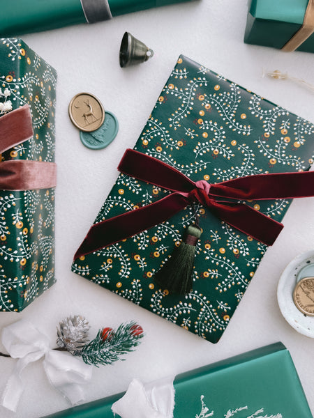 Christmas gift wrap decorated with dark red velvet ribbon bow and an olive green colored tassel