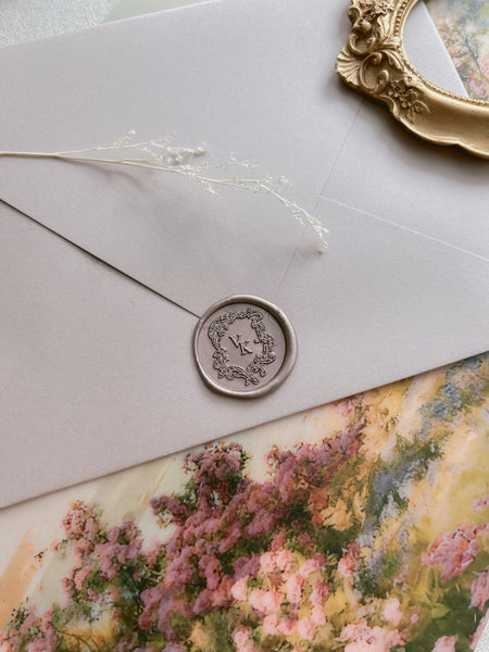 champagne gold colored vintage crest personalized monogram wax seal on a beige envelope and a floral print background