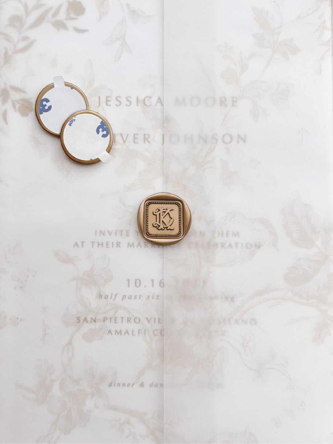 Gold vintage interlocked monogram border design square wax seals with adhesive backings on a beige floral print wedding invitation vellum jacket 
