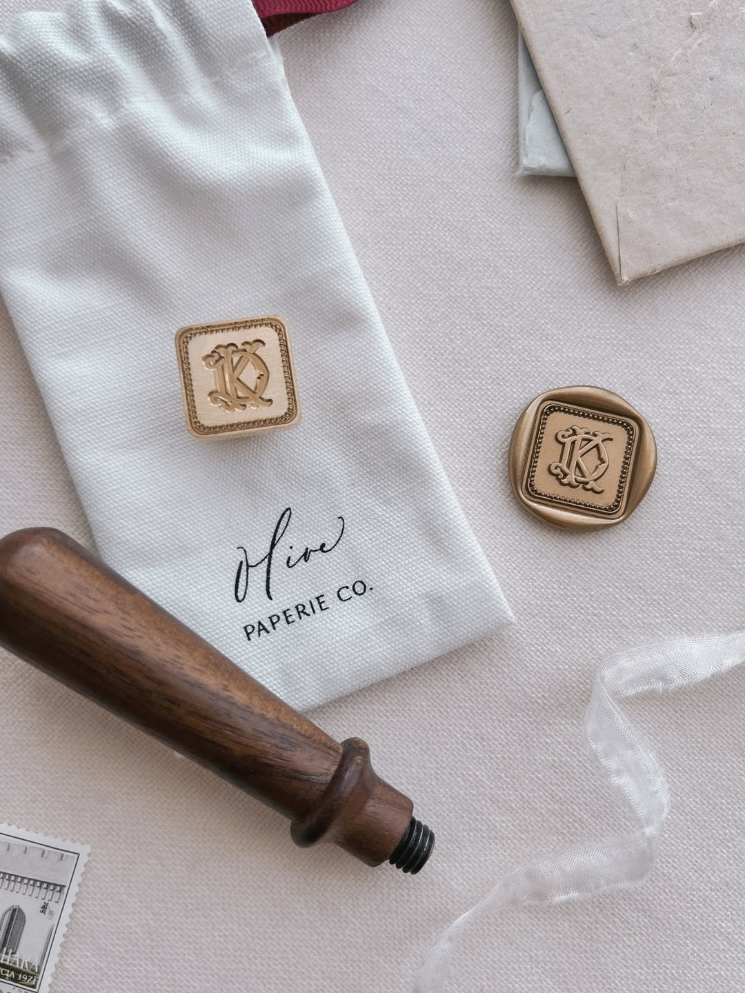 Wax stamp head and gold wax seal featuring personalized initials in vintage interlocked monogram font, next to a walnut wooden handle