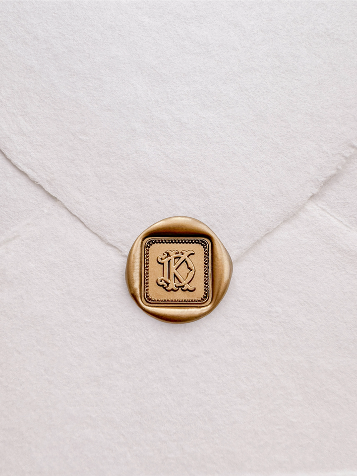 Personalized initials gold vintage square border wax seal featuring a custom monogram on a white deckled edge handmade paper envelope
