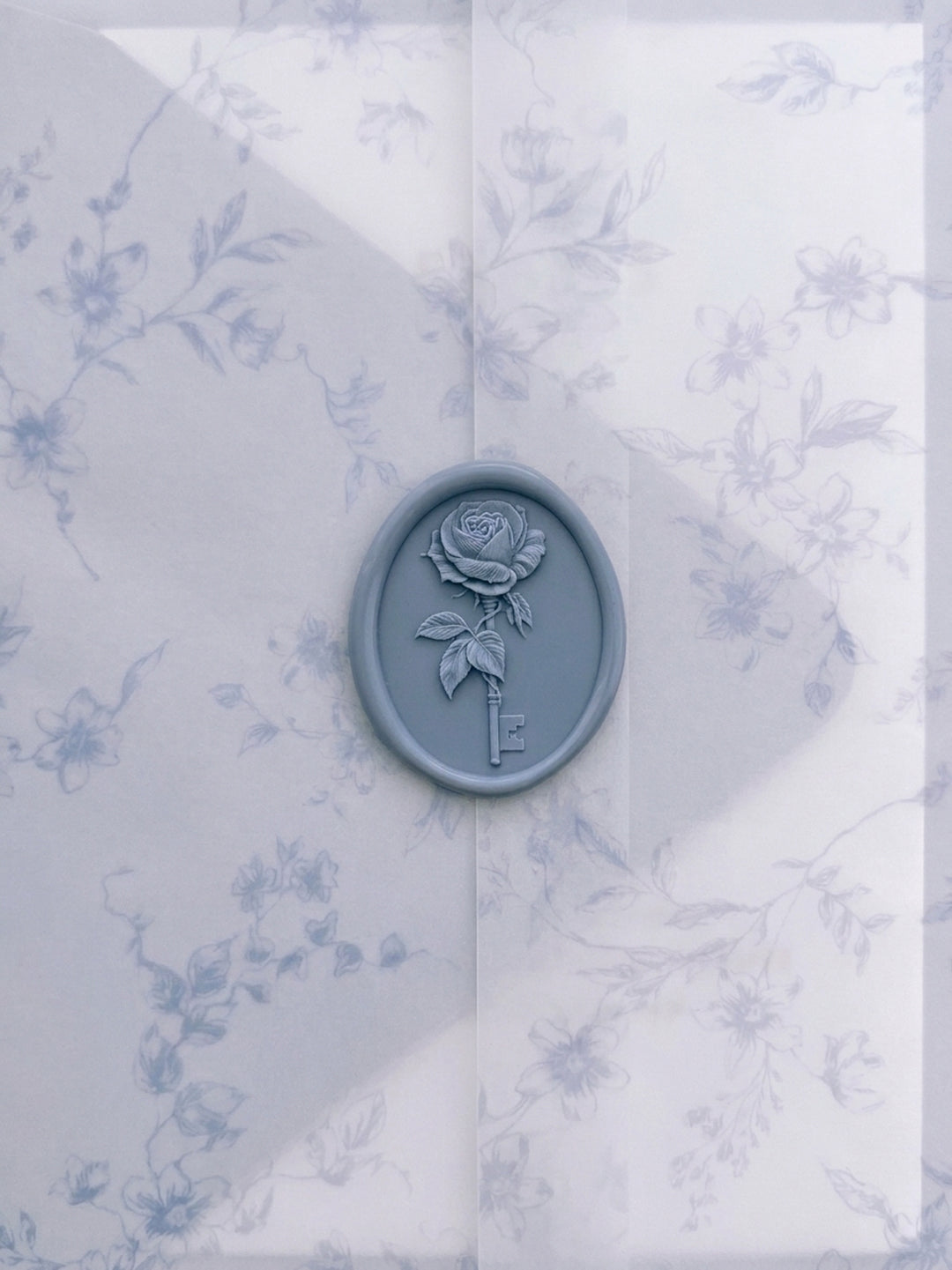 Dusty blue vintage rose key oval wax seal on a blue botanical print vellum jacket
