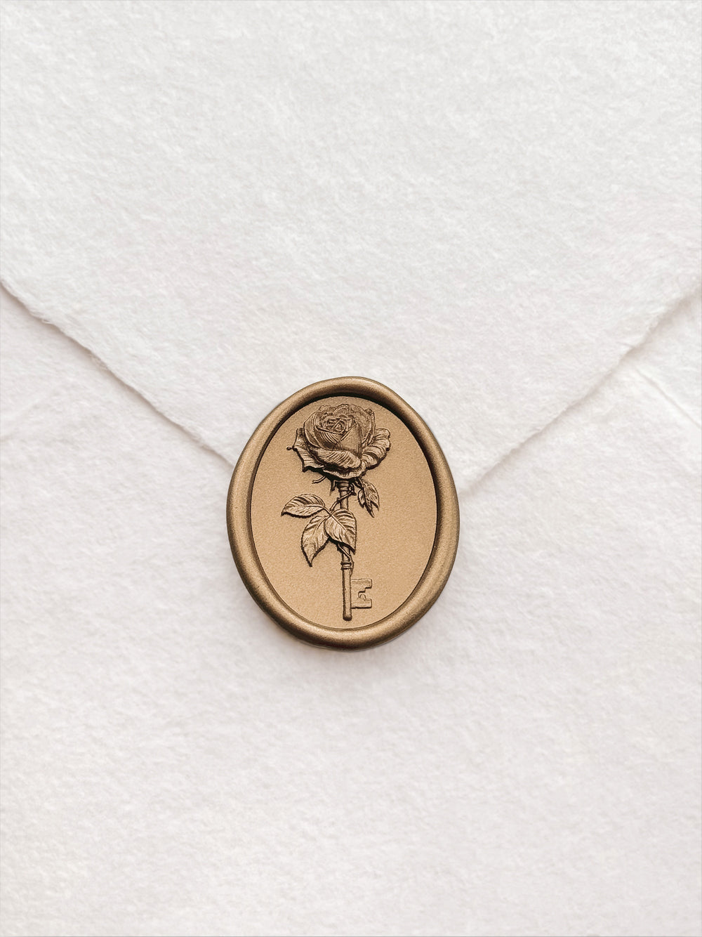 Gold vintage rose key oval wax seal on a white handmade paper envelope