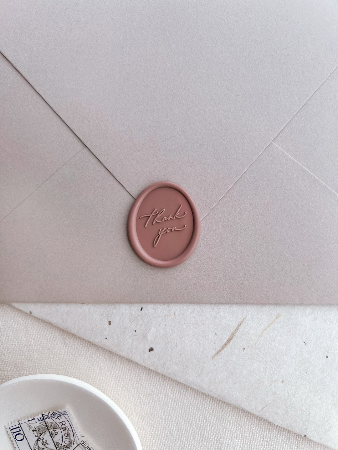 soft rose colored oval thank you wax seal on a pinkish beige envelope