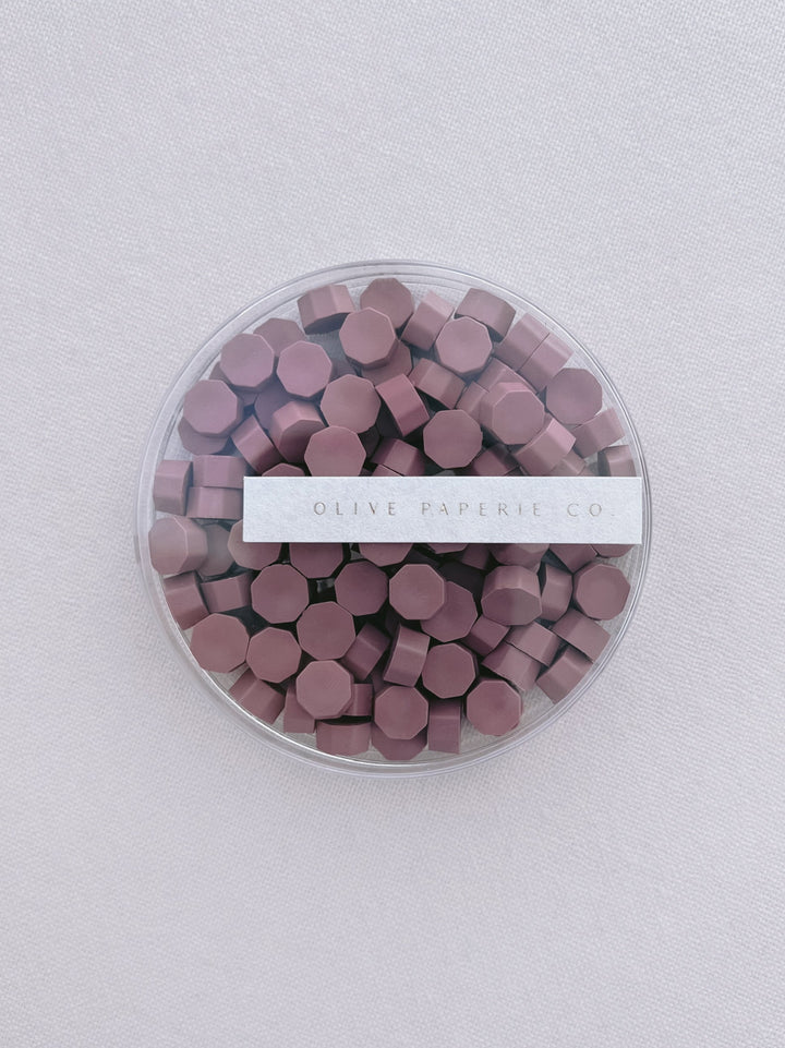 dusty rose colored wax seal beads in a clear container box