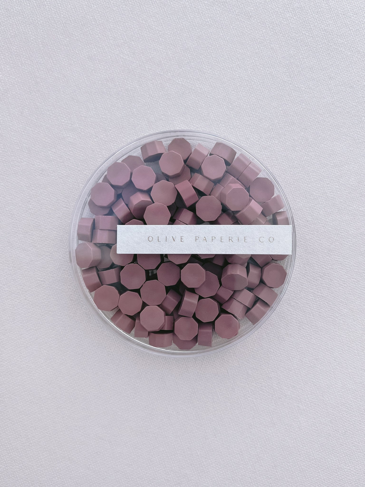 dusty rose colored wax seal beads in a clear container box