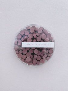dusty rose colored wax seal beads in a clear container box