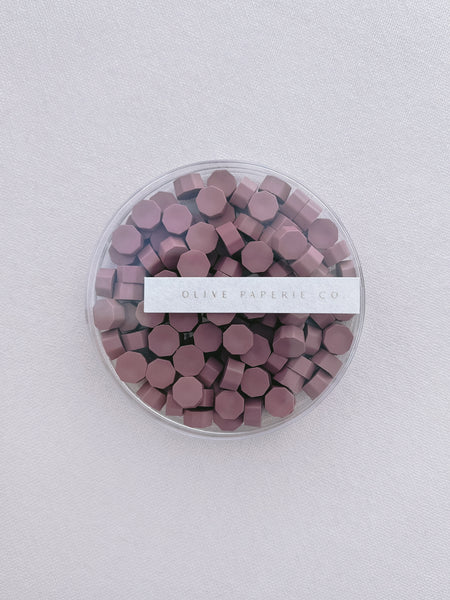 dusty rose colored wax seal beads in a clear container box