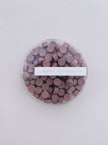 dusty rose colored wax seal beads in a clear container box