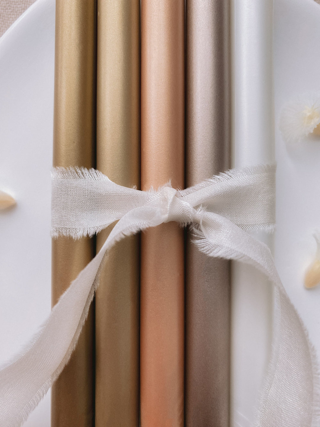 a set of 5 metallic earthy tones glue gun sealing wax sticks in gold, light gold, peachy gold, mocha, white pearl colors tied with soft white silk ribbon