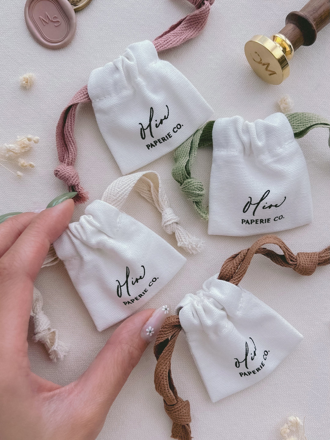wax stamp head cotton storage pouches in different drawstring colors — pink, green, beige, and brown