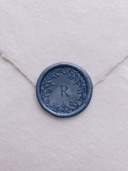 Floral crown single initial monogram wax seal in slate blue color on handmade paper envelope_front angle
